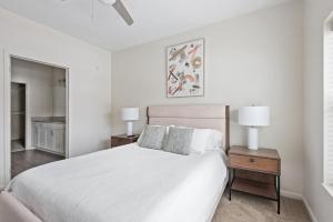ein weißes Schlafzimmer mit einem großen Bett und zwei Lampen in der Unterkunft Landing Modern Apartment with Amazing Amenities (ID7435X07) in Omaha