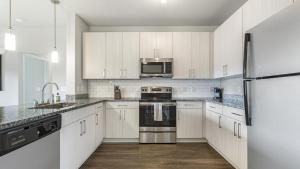 una cocina con armarios blancos y electrodomésticos de acero inoxidable en Landing Modern Apartment with Amazing Amenities (ID1256X568), en Greenville