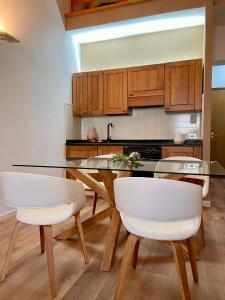 a kitchen with a glass table and white chairs at Amiata Loft Design - Monte Amiata - Free Parking in Seggiano
