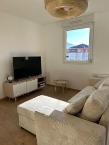 a living room with a couch and a flat screen tv at Superbe appartement T3 en résidence avec piscine in Albertville