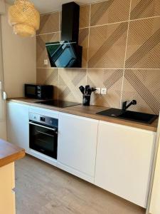 cocina con fregadero y TV en la pared en Superbe appartement T3 en résidence avec piscine, en Albertville