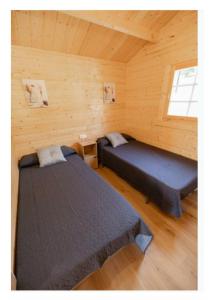 a room with two beds in a log cabin at BUNGALOWS MARTINA in Coó
