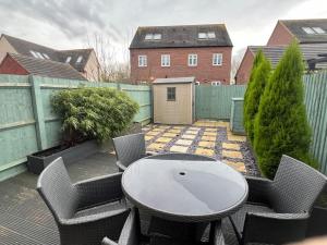un patio con mesa, sillas y una valla en Braid House en Loughborough