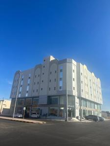 un gran edificio con coches estacionados en un estacionamiento en فندق زائر الشمال en Hail