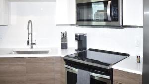 uma cozinha com um micro-ondas e um fogão forno superior em Landing Modern Apartment with Amazing Amenities (ID2665X75) em Fort Lauderdale