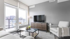 uma sala de estar com uma televisão, um sofá e uma mesa em Landing Modern Apartment with Amazing Amenities (ID8566X33) em Vancouver