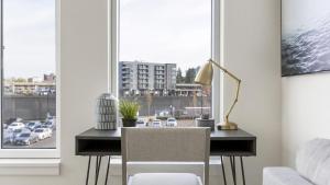 uma secretária com um candeeiro e uma cadeira em frente a uma janela em Landing Modern Apartment with Amazing Amenities (ID8566X33) em Vancouver