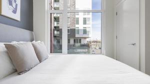 um quarto com uma grande cama branca e uma janela em Landing Modern Apartment with Amazing Amenities (ID8566X33) em Vancouver