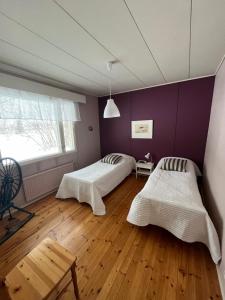 2 Betten in einem Zimmer mit lila Wänden und Holzböden in der Unterkunft Kujalan tila 