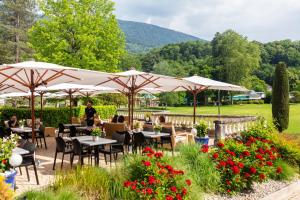 a restaurant with tables and umbrellas in a garden at Grand Hôtel & Spa Uriage in Uriage-les-Bains