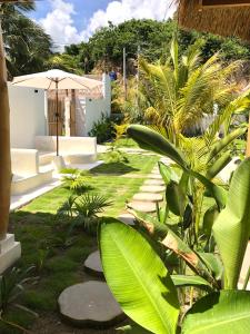 un jardín con plantas verdes y una sombrilla en Luana Lombok, en Selong Belanak