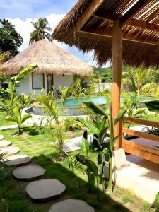 a resort with a swimming pool and a straw hut at Luana Lombok in Selong Belanak