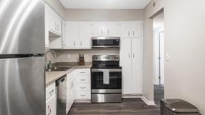 una cocina con armarios blancos y un aparato de acero inoxidable en Landing Modern Apartment with Amazing Amenities (ID1008X640) en Homewood