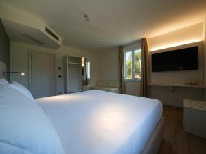 a bedroom with a large white bed and a television at Castiglioncello Suite in Castiglioncello
