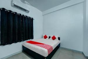 As Hotels & Banquet في Hazārībāg: غرفة نوم بسرير مع ستائر سوداء ومخدات حمراء