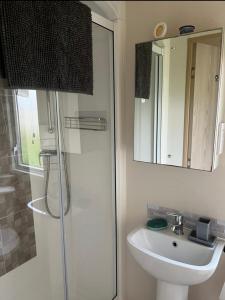 a bathroom with a shower and a sink and a mirror at GDs Luxury Caravan Hire Turnberry Holiday Park in Turnberry