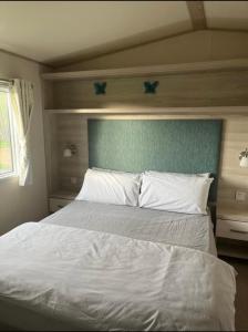 a bedroom with a white bed with a blue headboard at GDs Luxury Caravan Hire Turnberry Holiday Park in Turnberry