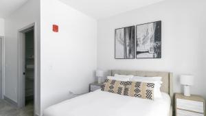 a white bedroom with a bed and a picture on the wall at Landing Modern Apartment with Amazing Amenities (ID1791X13) in Richmond