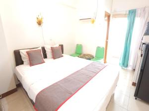 a bedroom with a large bed with two green chairs at Aurora Rooms @ Apartemen Loftvilles City in Dukuh