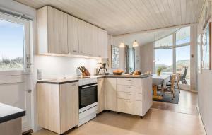 a kitchen with white cabinets and a dining room with a table at Holiday Home Henriettevej Hvide Sande Ix in Bjerregård +22 photos