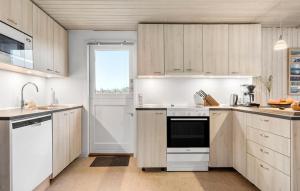 a kitchen with white cabinets and a window at Holiday Home Henriettevej Hvide Sande Ix in Bjerregård