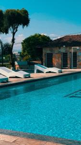 a swimming pool with white lounge chairs next to a house at O Paturi - Village Hotel in Guaratinguetá