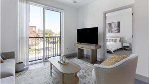 uma sala de estar branca com uma televisão e um sofá em Landing Modern Apartment with Amazing Amenities (ID1791X17) em Richmond