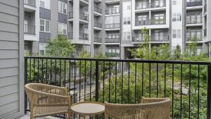 einen Balkon mit 2 Stühlen, einem Tisch und einem Gebäude in der Unterkunft Landing Modern Apartment with Amazing Amenities (ID1208X667) in Decatur