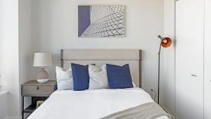 Landing Modern Apartment with Amazing Amenities (ID1398X857) في ناشفيل: غرفة نوم بيضاء مع سرير ووسائد زرقاء