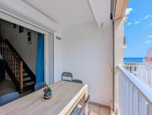 a balcony with a wooden table and chairs on it at Appartement T4, climatisation, 50m de la plage in Cap d'Agde