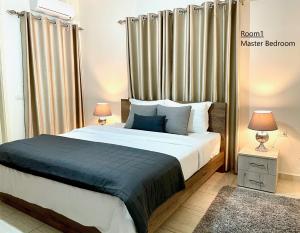a bedroom with a large bed with two lamps and a window at Elite Residence - Furnished Apartments in An Nakhlah