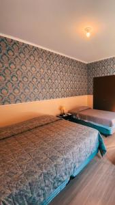 1 dormitorio con 2 camas y pared con papel pintado en O Paturi - Village Hotel, en Guaratinguetá