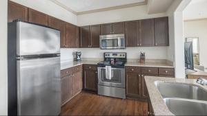 La cuisine est équipée d'armoires en bois et d'un réfrigérateur en acier inoxydable. dans l'établissement Landing Modern Apartment with Amazing Amenities (ID1192X865), à Houston
