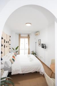 um quarto com uma cama grande e lençóis brancos em Naim Guest House Nerja em Nerja