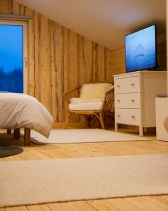 een slaapkamer met een bed, een tv en een stoel bij BLUEBERRY LODGE 5 personnes in Mjölan