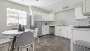 uma cozinha com uma mesa e cadeiras e um frigorífico em Landing Modern Apartment with Amazing Amenities (ID1232X656) em Las Vegas