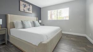 um quarto com uma cama com lençóis brancos e uma janela em Landing Modern Apartment with Amazing Amenities (ID1232X656) em Las Vegas