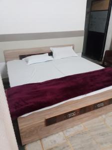 a large bed with white sheets and a purple blanket at OP Krishna Homestay in Mathura