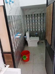 a small bathroom with a toilet and a bucket at OP Krishna Homestay in Mathura