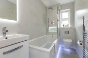 a white bathroom with a tub and a toilet and a sink at Stanley House in Reading
