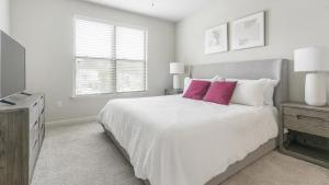 um quarto branco com uma cama grande e almofadas cor-de-rosa em Landing Modern Apartment with Amazing Amenities (ID1210X718) em Wake Forest