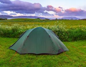 a green tent in the middle of a field at Klokkehøj in Ullerslev