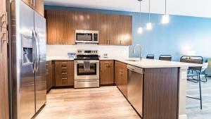 uma cozinha com utensílios de aço inoxidável e armários de madeira em Landing Modern Apartment with Amazing Amenities (ID1954) em Aurora
