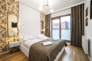 a bedroom with a large bed and a large window at Apartament Amber Centrum z basenem in Gdańsk