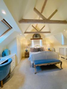 a bedroom with a large bed and a blue chair at Campden Mews in Chipping Campden