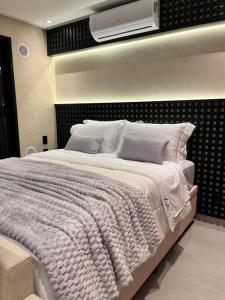 a bedroom with a white bed with a tv on the wall at Lindo estúdio em Marilia - ao lado do Ibis in Marília