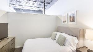 a white bedroom with a bed and a television at Landing Modern Apartment with Amazing Amenities (ID9106X83) in Omaha