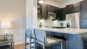a kitchen with a counter with chairs and a refrigerator at Landing Modern Apartment with Amazing Amenities (ID1413) in Houston