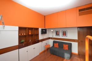 Zimmer in Orange und Weiß mit einem Stuhl und Schränken in der Unterkunft The Serra Vision in Ivrea