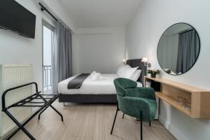 ein Schlafzimmer mit einem Bett, einem Spiegel und einem Stuhl in der Unterkunft Hotel Adonis Athens in Athen